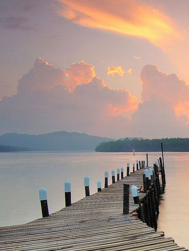 pier extending over water with sunset in the background