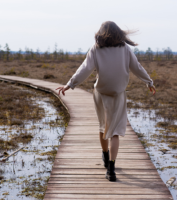 happy girl walking on a beach boardwalk with her arms out to balance